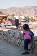 Fototapeta premium Arab girl standing on the promenade of Dahab back to the photographer