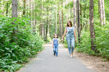 Family, children and nature concept - Portrait of attractive woman and little child girl walking together