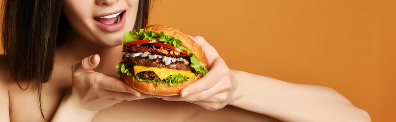 Fast food concept. Tasty unhealthy burger sandwich in hands hungry mouth getting ready to eat on...