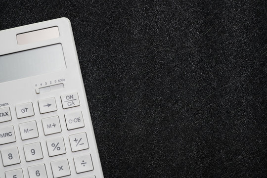 White clean calculator on dark texture black background with copy space using as budget, math, finance or savings concept