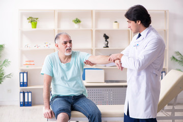 Fototapeta premium Old man visiting young male doctor 