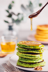 Green pancakes with matcha tea or spinach, dressed honey and red grapes. Healthy breakfast with...