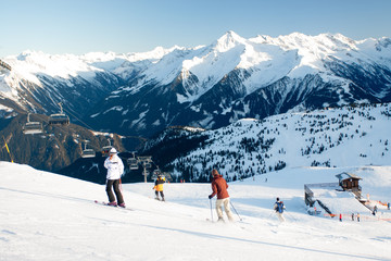 Ski lift and ski slope with skiers under it on sunny winter day with blue sky.