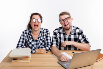 Nerds, geek, bespectacled and funny people concept - funny student couple in glasses sitting at the table