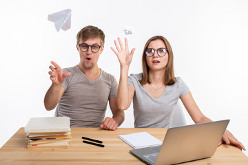 Playful, naughty students with big glasses throwing paper airplanes and crumpled paper sitting at...