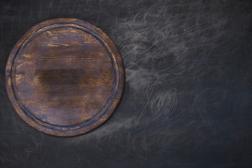 Round wooden plate on dark gray background top view 