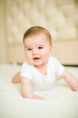 Portrait of cute baby girl lying down on a bed.