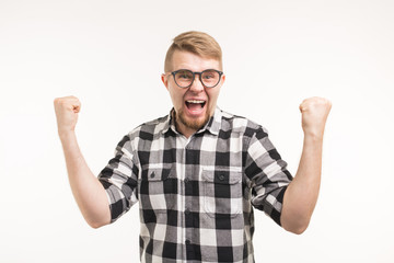 Naklejka premium People, emotions and triumph concept - Excited and happy young man dressed in shirt showing fists up on white background.