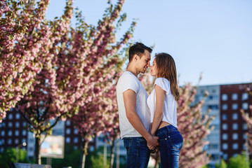 Passion and love concept. Man and woman kissing in blooming garden on spring day. Couple hugs near sakura trees. Couple in love spend time in spring garden, flowers on background, defocused, close up