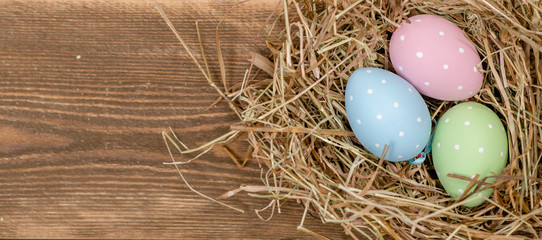 Easter eggs in a natural straw nest. Top view. Empty space for text