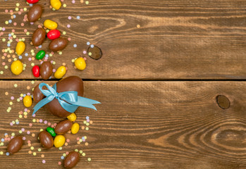 Candies and chocolate Easter eggs on wooden background. Top view. Space foe text