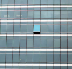 The glass facade of skyscraper with many identical windows and only one window is different. Same...