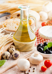 Homemade spaghetti pasta with quail eggs with botle of olive oil and cheese on wooden background. Classic italian village food. Garlic, black and green olives, oil and bread. Basil leaf
