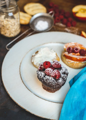 sweet breakfast plate - chocolate muffin with fresh raspberries, baked bun with apples and cinnamon