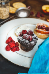 sweet breakfast plate - chocolate muffin with fresh raspberries, baked bun with apples and cinnamon