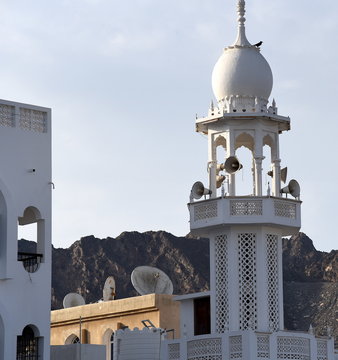 Wei&szlig;es Minarett mit Satelittensch&uuml;sseln und Bergen im Hintergrund