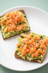Avocado Räucherlachs Vollkorn Sonnenblumenkern Brot und Sesam zum Frühstück auf grünen Hintergrund