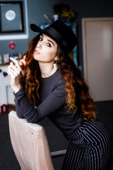 Sexy girl model with long curly hair in a black hat