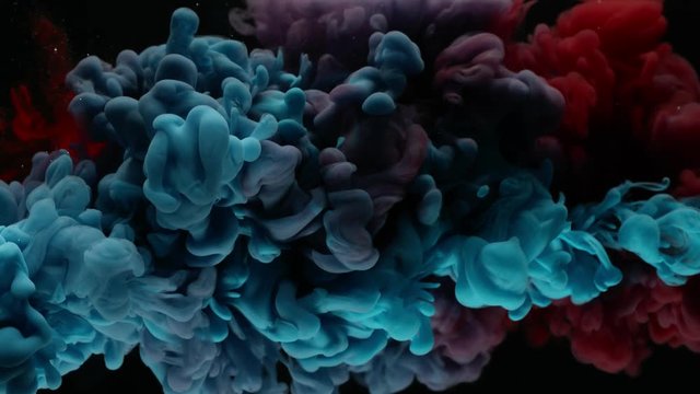 Super slow motion of coloured inks in water. Isolated on black background. Filmed on high speed cinema camera.