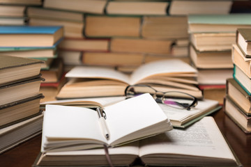 Open book and glasses on wood desk in the library room with blurred focus for education background and back to school concept