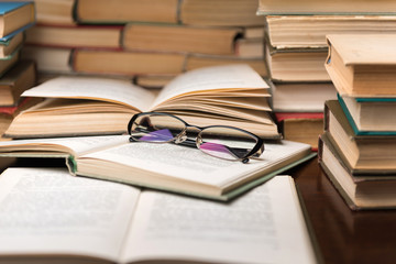 Open book and glasses on wood desk in the library room with blurred focus for education background and back to school concept