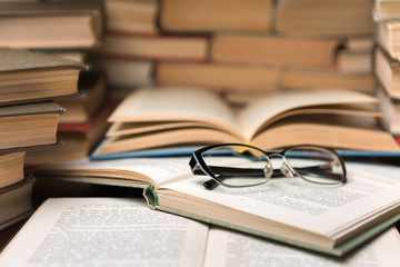 Old open books in library, stack piles of literature text archive on reading desk in school study class room, background for education learning concept. Narrow depth of field
