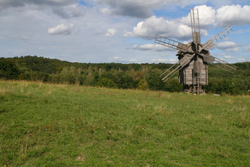 Wooden windmill, green trees, blue sky with white clouds