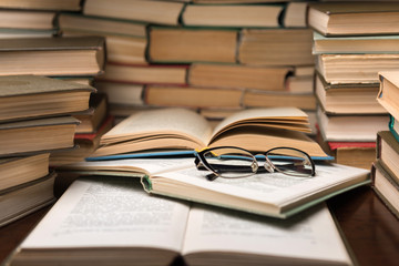 Open book and glasses on wood desk in the library room with blurred focus for education background and back to school concept