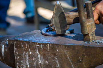 blacksmith performs the forging of hot glowing horseshoe on the anvil