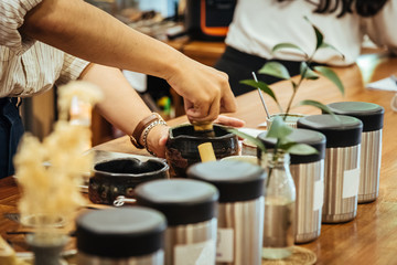 Japanese tea brewing process, green tea in clay pot with tool on the wood bar with man hand.
