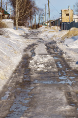 winter road covered with snow and ice with puddles and ruts