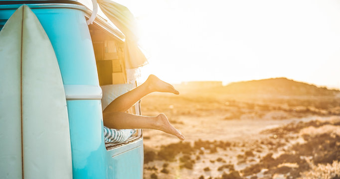 Legs view of happy surfer girl inside minivan at sunset - Focus on feet