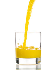 Pouring orange juice into a transparent glass on a white background