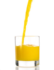 Pouring orange juice into a transparent glass on a white background