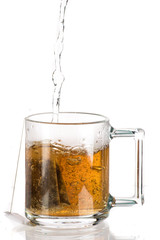 Making tea with sugar from a tea bag in a transparent mug on a white background