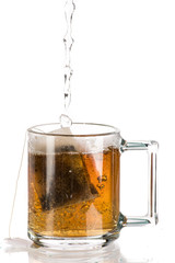 Making tea with sugar from a tea bag in a transparent mug on a white background