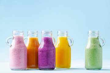 Fototapeta na wymiar Summer colorful fruit smoothies in jars on blue background. Healthy, detox and diet food concept.