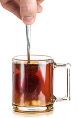 Making tea with sugar from a tea bag in a transparent mug on a white background