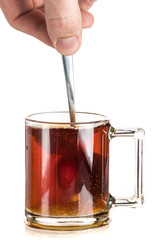 Making tea with sugar from a tea bag in a transparent mug on a white background