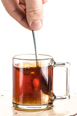 Making tea with sugar from a tea bag in a transparent mug on a white background