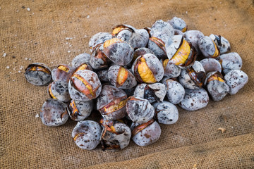 European delicacy roasted chestnuts sold at streets on a burlap background.