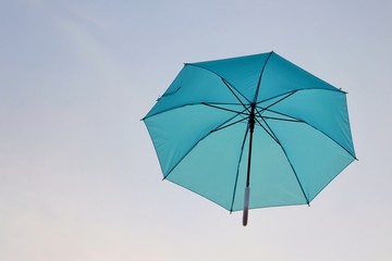 Fototapeta na wymiar blue umbrella floating on the air, isolate on sky background, sunset