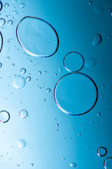 Beautiful macro photo of water droplets in oil with a blue background.