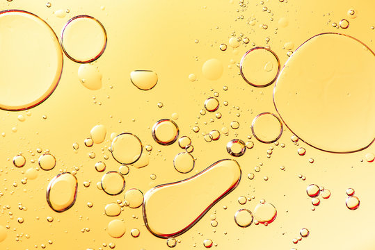Beautiful macro photo of water droplets in oil with a yellow background.