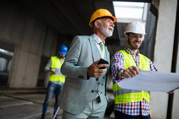Engineer and construction site manager dealing with blueprints and plans