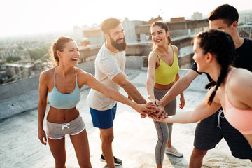 Group of young happy people friends exercising outdoors at sunset.