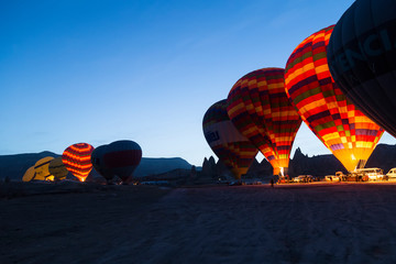 Obraz premium the balloons get ready to departure in Cappadocia from Turkey. People watch them in morning times.