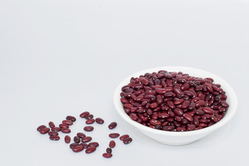 Grains of red beans in a white plate on a gray background