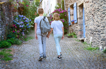 Fototapeta na wymiar Old villge in Europe with blossom bushes of hydrangea. Teenagers people and travel concept. Teens walking in the streets of old town.