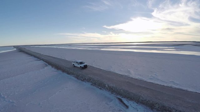 Aerial rolling shot shot of a pickup in the salt flats by solar evaporation in Guerrero Negro, Ojo de Liebre lagoon, Biosphere Reserve of El Vizcaino, Baja California Sur.